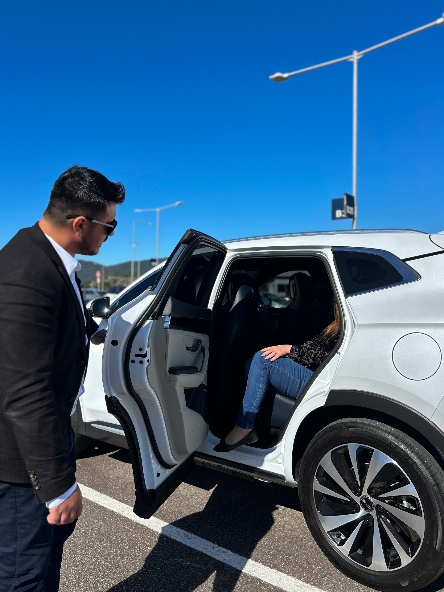 Motorista executivo da Douglas Transfer recepcionando cliente ao lado do SUV branco em Florianópolis