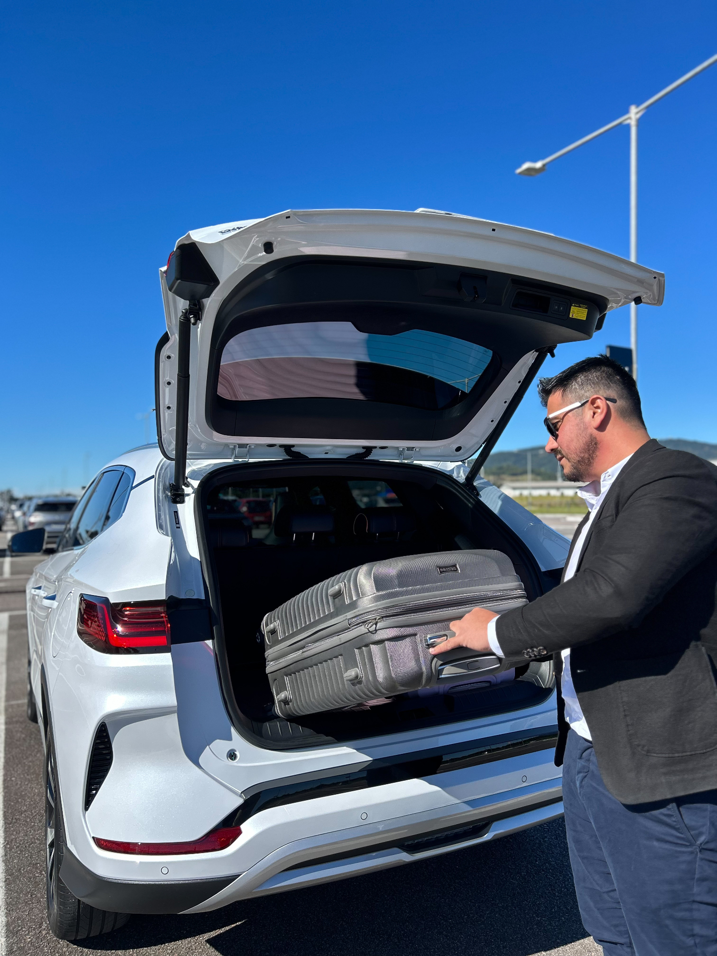 Motorista acomodando mala no porta-malas do SUV executivo durante transfer aeroporto